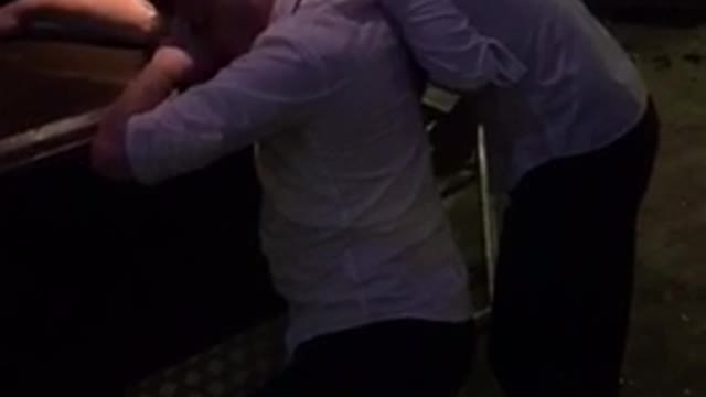 Two drunk guys at bar in white dress shirts fall over to the ground