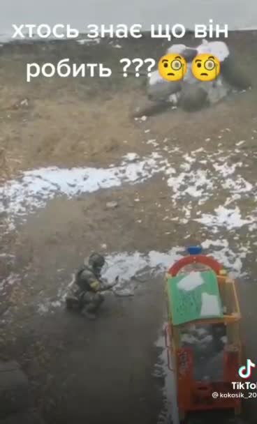 A Ukrainian sapper in a protective suit carries an IED / Molotov cocktail to the playground
