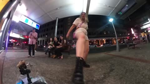 Woman Kicks Robot Dog Walking Down Sidewalk