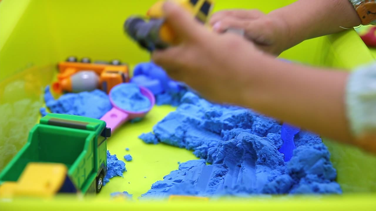 Child's Hand Playing Toy Sand at Home
