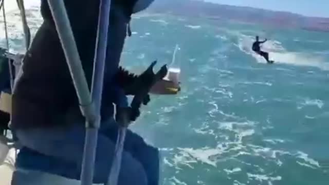 Kite Surfer Picks Up Bottle From Guy On Boat And Drinks From It