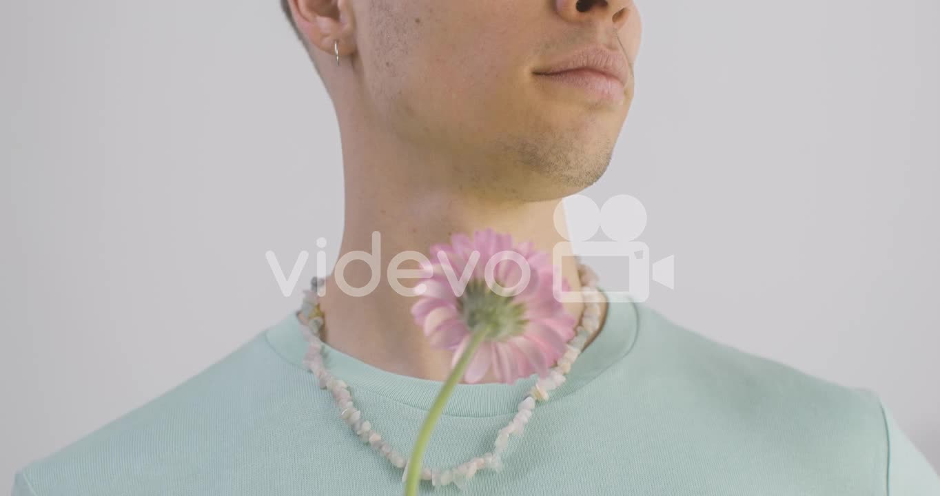 Handsome Man With Green T Shirt And Necklace Holding Flower