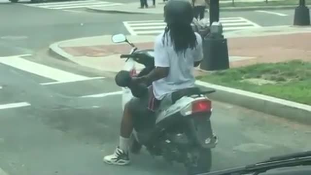 A man with long hair does not forget to exercise when riding a bike