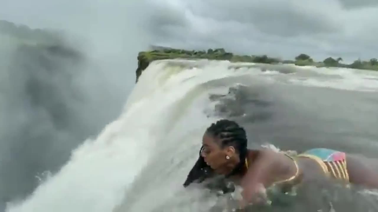 Woman laying down inches before a massive 380 feet drop, devils pool - Victoria falls