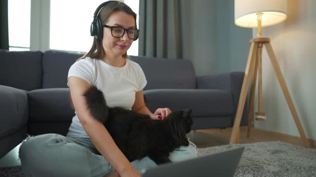 Casually dressed woman sits on a carpet with a laptop
