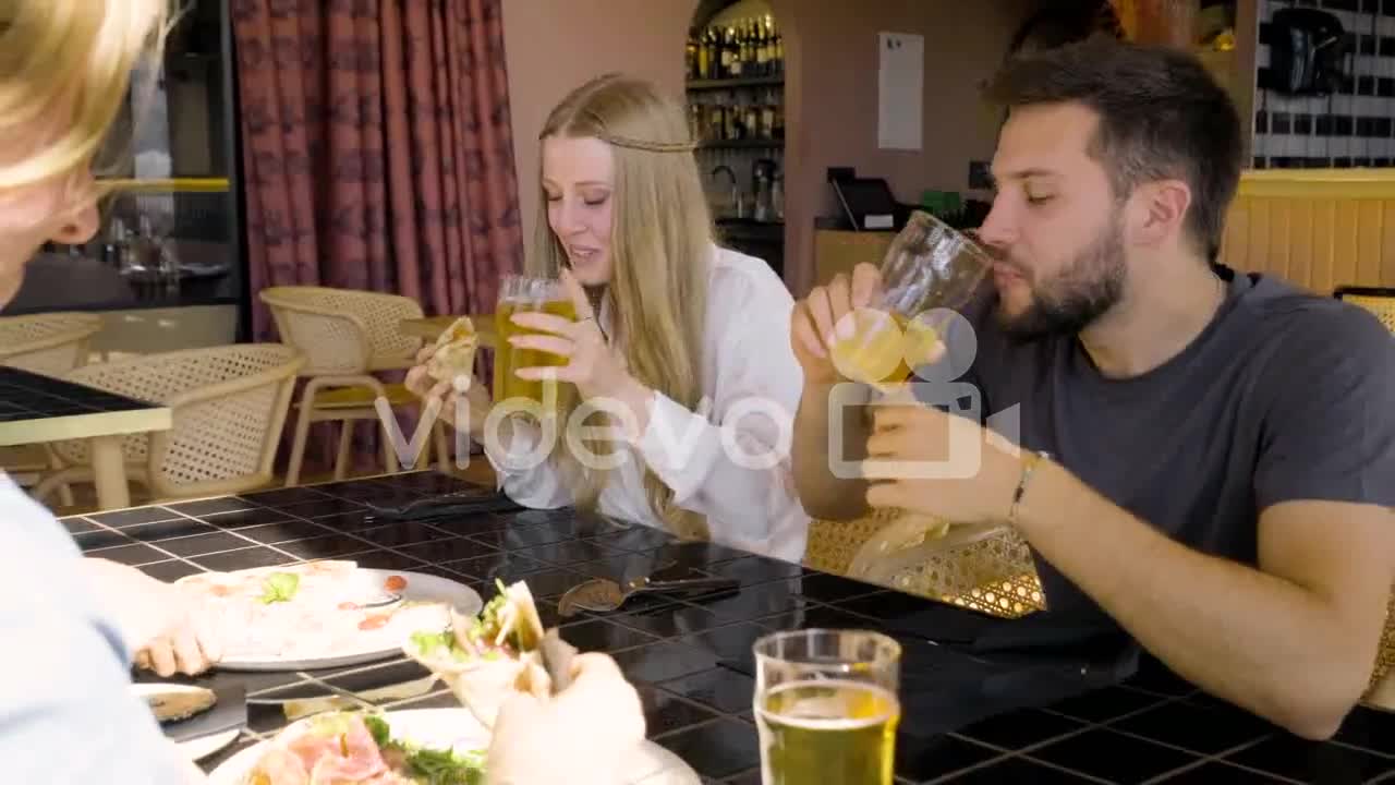 Close Up View Of A Woman And Man Talking And Eating Pizza With Their Friends At Restaurant Table 2