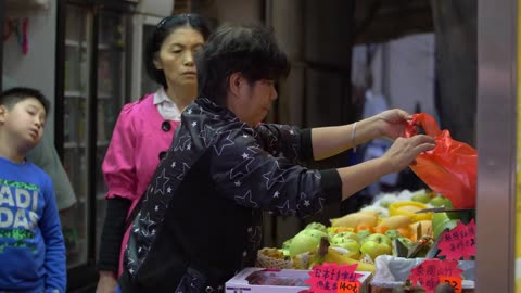 Lady Weighing Fruit at a Market Stall