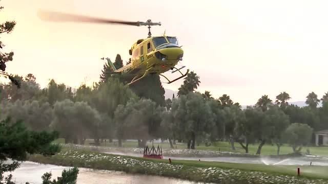 Helicopters use water from golf course to battle wildfire in Spain