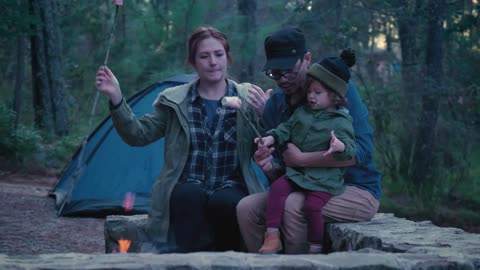 Parents and their daughter roasting marshmallows in a forest