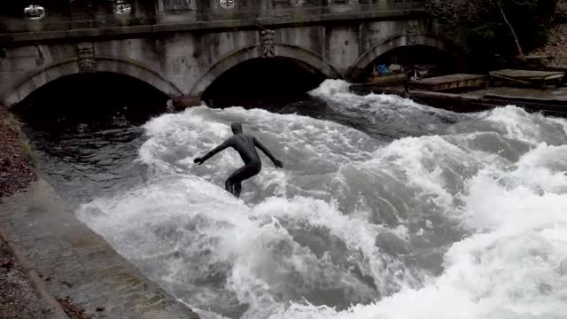 Person Surfing in Black Suit at a Canal