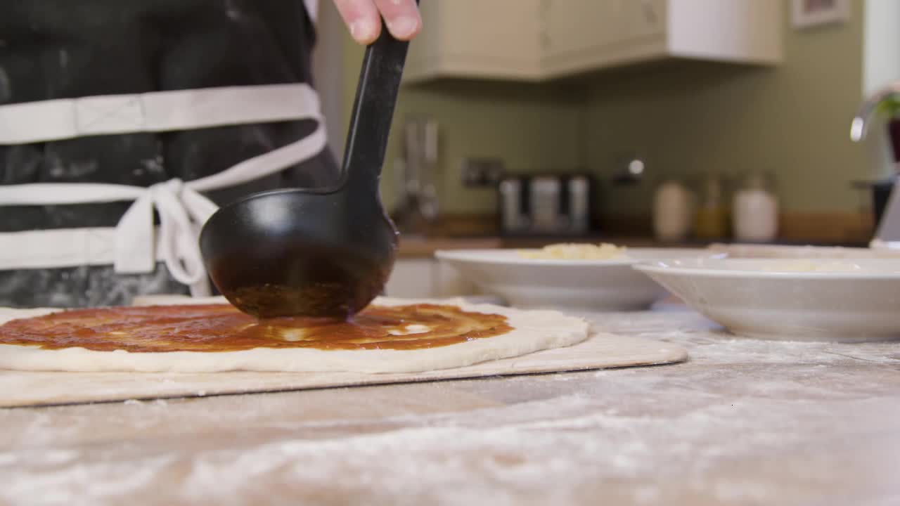 Male Spreading Tomato Sauce on Pizza Dough