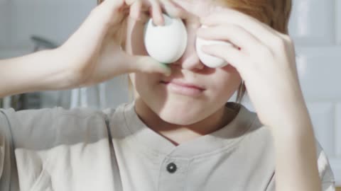 A Boy Playing With Eggs By Putting It Over His Eyes