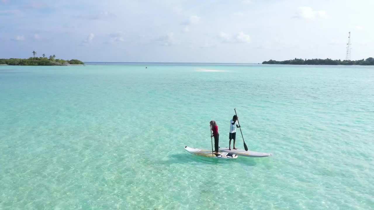 A couple paddling on boards on turquoise sea