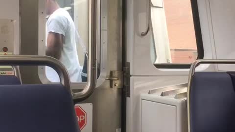 Guy standing outside between two subway carts trains