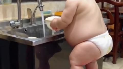 Young sumo wrestler washing dishes