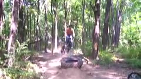 Music grey wifebeater guy on bicycle jumps tire crashes into tree