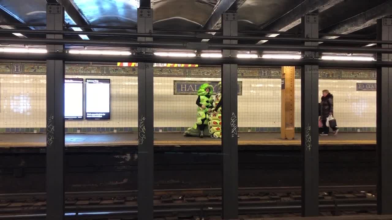 Two people green caterpillars dancing subway platform