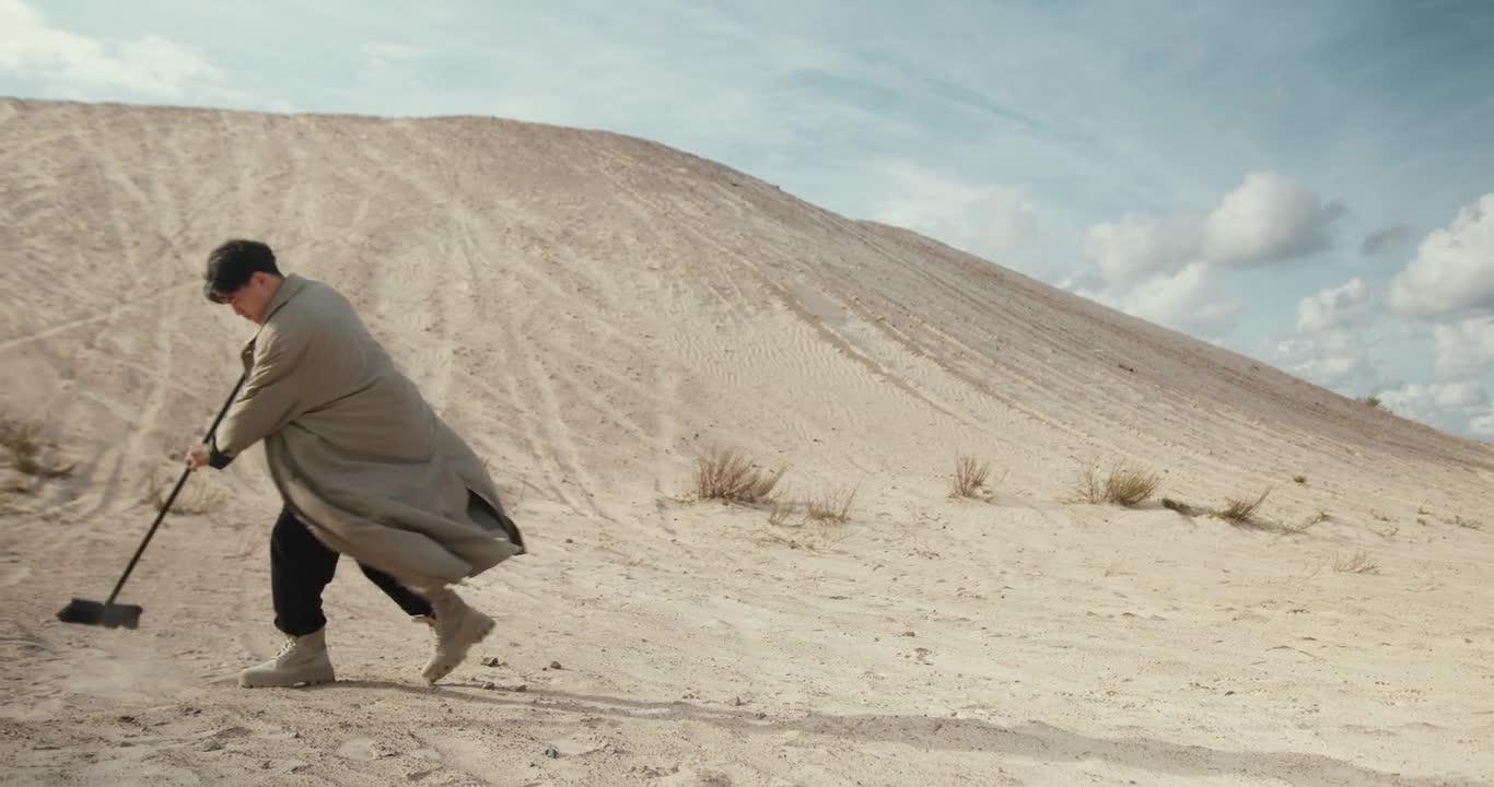 Man Sweeping Sand on a Desert