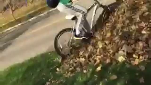 Guy in green shirt riding bike falls down