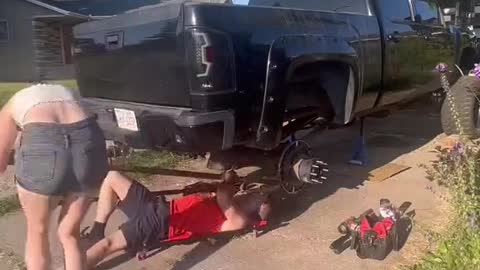 A mechanic repairs a car with his girlfriend