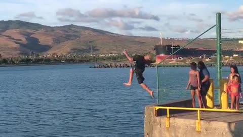 Guy parkour runs off of dock pier and into water front flip