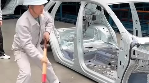 Worker smashing a car in the factory