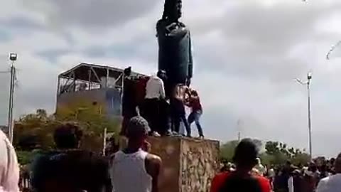 Protesters have started knocking down the statue of Hugo Chávez in the square