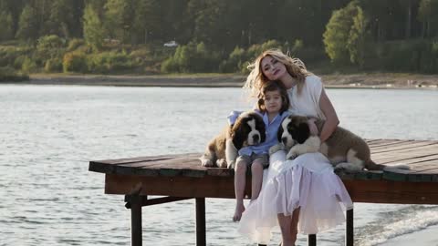 Little boy with mother near the sea playing with their dogs