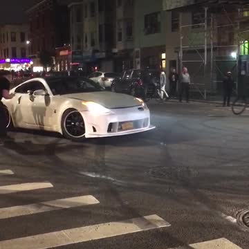 Two cars doing donuts on street white car drives around