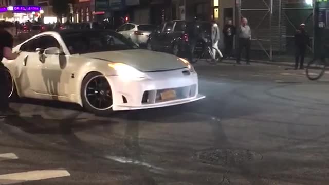 Two cars doing donuts on street white car drives around