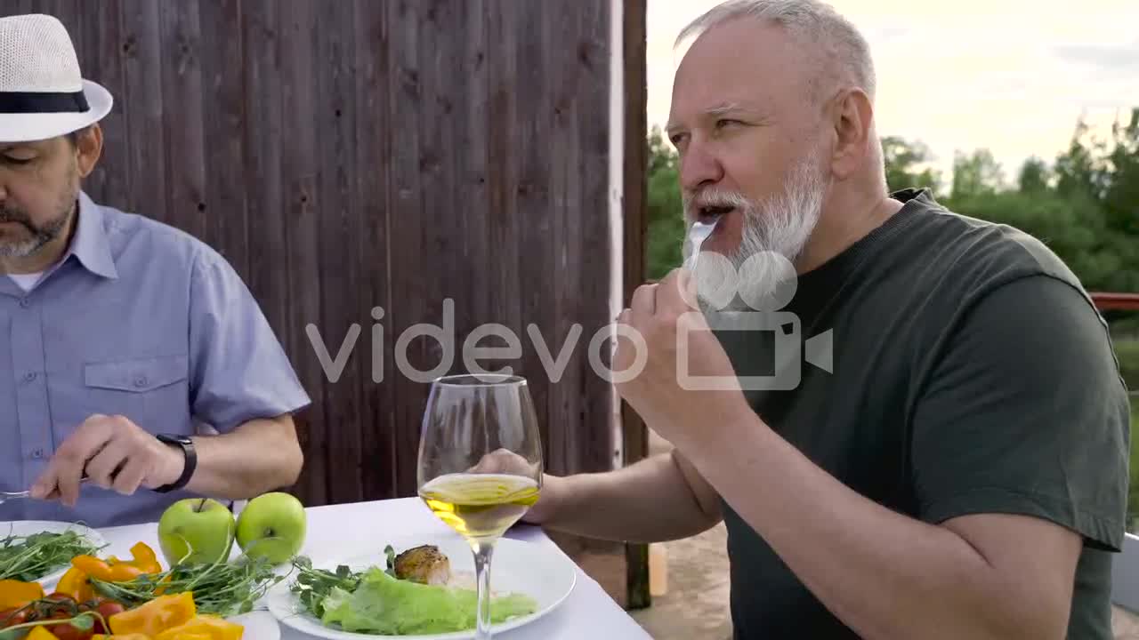 A Couple Of Senior Friends Having Dinner Outdoors
