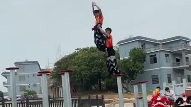 Two Dancers Practice Traditional Chinese Lion Dance Over Poles in Water