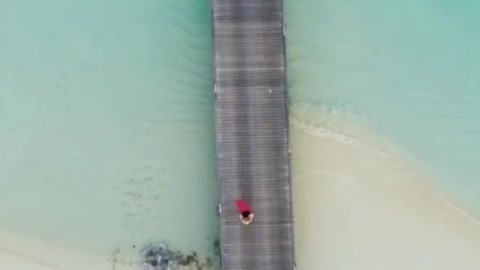 Woman waving from a pier at the beach