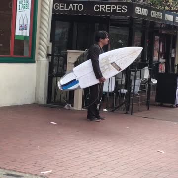 A man carrying a surfboard in a black wet suit