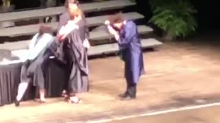 Guy walking across graduation stage trips and falls