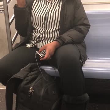 Woman in black and white shirt sings out loud on subway