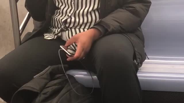 Woman in black and white shirt sings out loud on subway