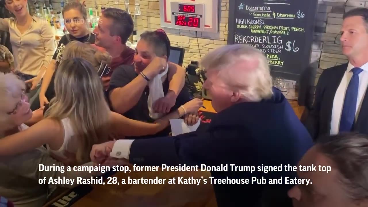 Trump autographs woman's tank top shirt at Iowa campaign stop