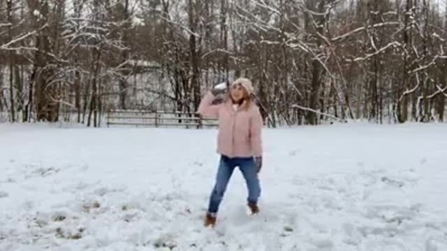 Husband makes his wife engage in playing throwing snow with him when she talking on the stream.