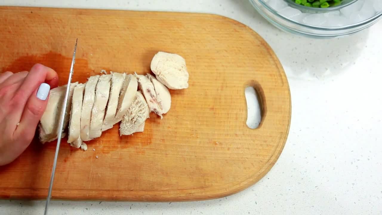 Hands woman cuts boiled chicken with knife on a wooden board food