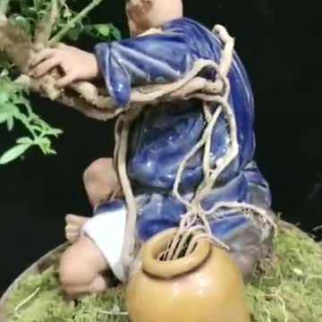 Bonsai pots with growing plants cover the statue nicely