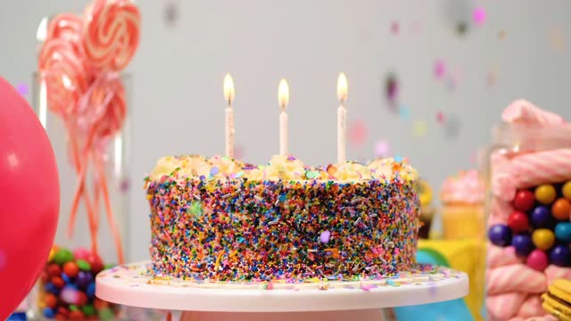 Birthday cake on a table with candies and balloons