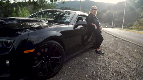 Woman leaning against luxury black car