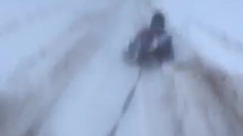 Guy sledding on a frozen beach tied to a car