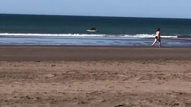 Surfer in the distance does push ups on his surfboard while on the water