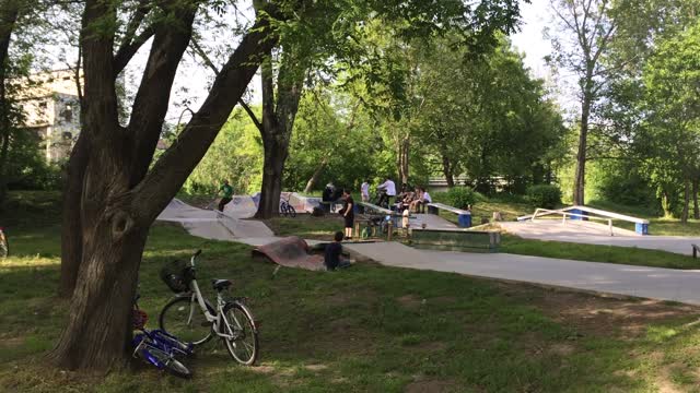 Skater ollies off ramp, lands in grass and falls down on back