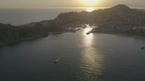 Boats and motorboats sailing along a coastline during sunset