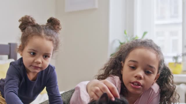 kids petting their cat on the bed.so cute