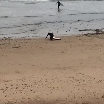 Guy in black wetsuit stretching near at beach