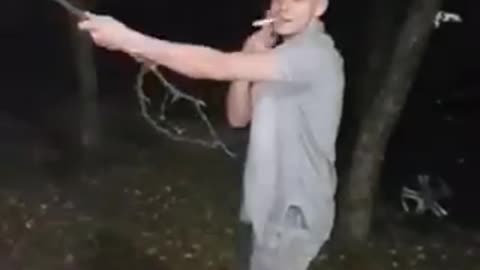 Guy blue shirt smoking hanging from tree branch